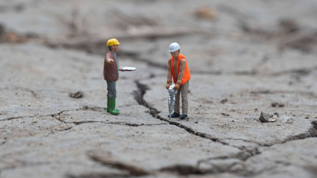 two model construction workers on a cracked concrete surface