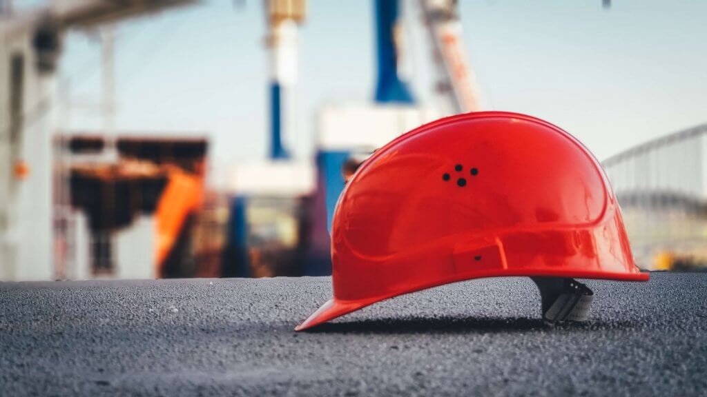 Red hard hat with building site in background