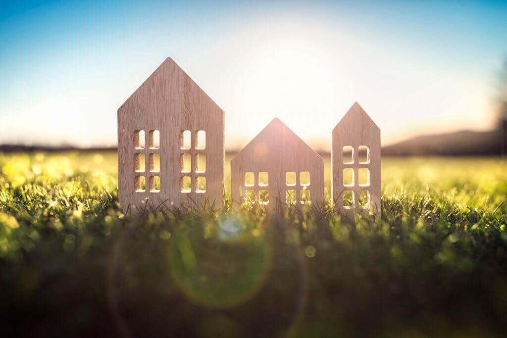 model wooden houses on a grass field in the sun